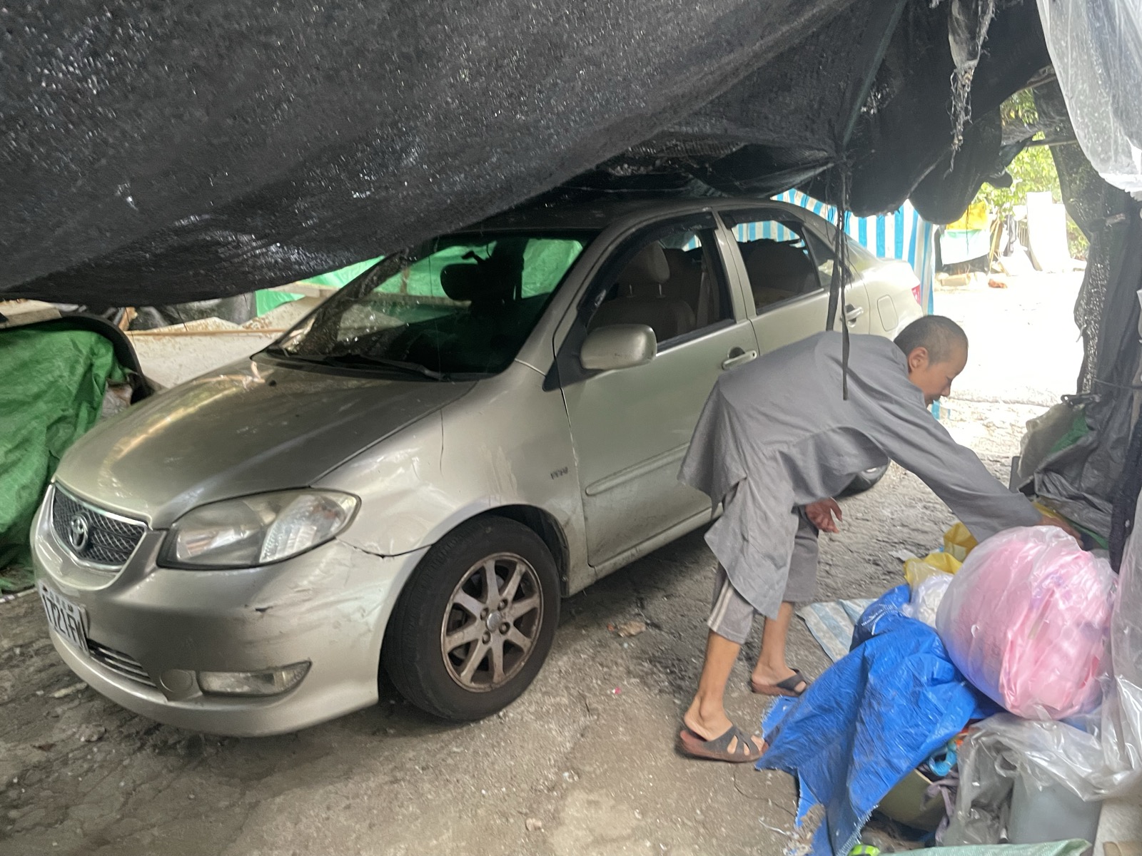 師父在屋簷下的車旁工作